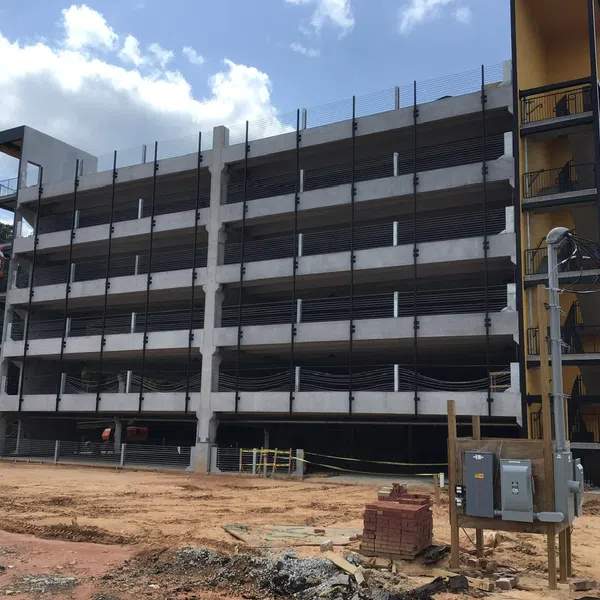 Multi-level concrete parking garage under construction with construction equipment and materials on site under blue sky.