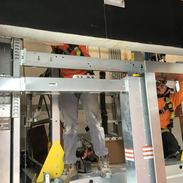 Construction workers installing metal framing with safety gear on site during building renovation.