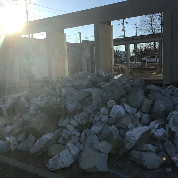 Pile of rubble and concrete debris at a partially demolished building site with sunlight in background