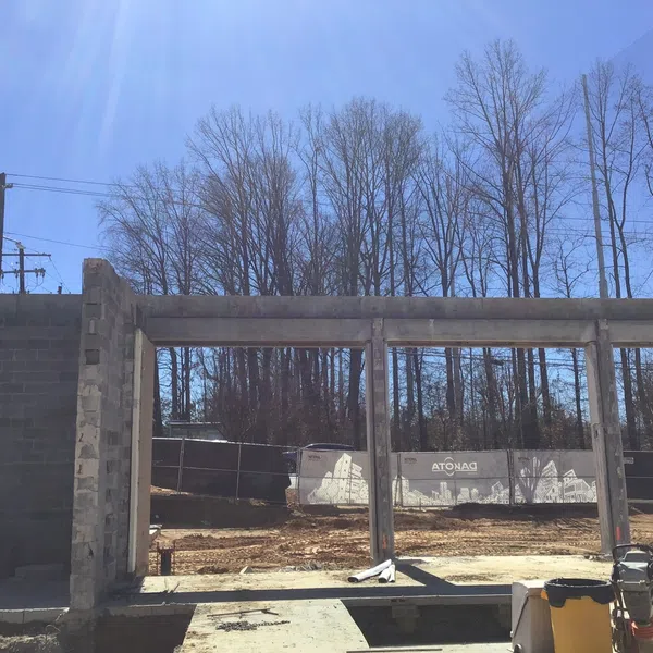Partially built concrete frame structure on a sunny day with bare trees and clear blue sky in the background.