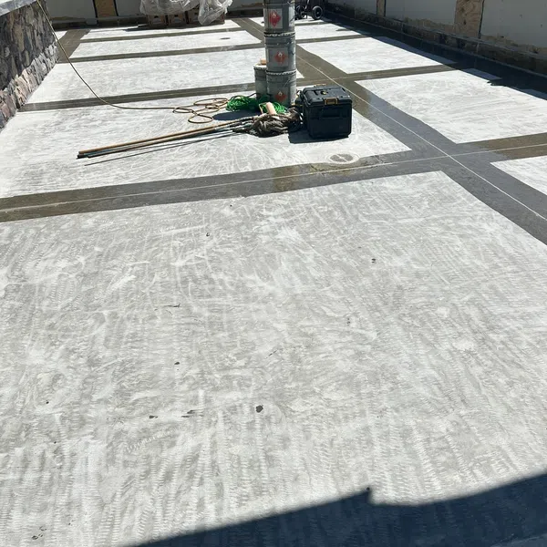 Concrete patio under construction with tools, buckets, and a toolbox on a sunny day outdoors.