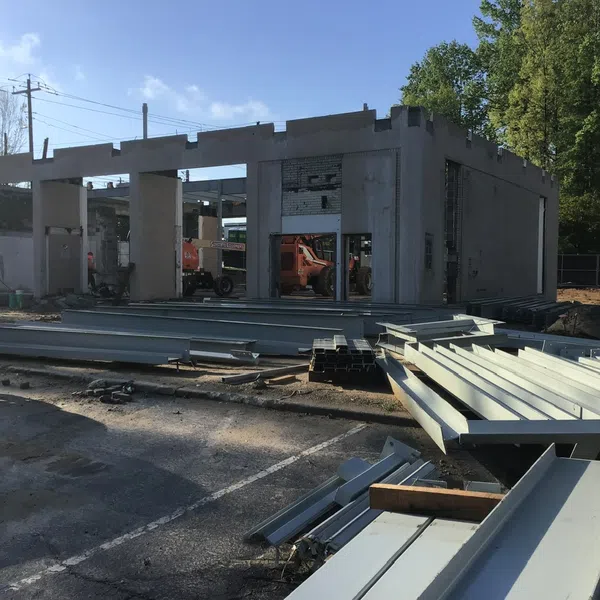 Construction site with steel beams and partially built concrete structure under clear sky during daytime.