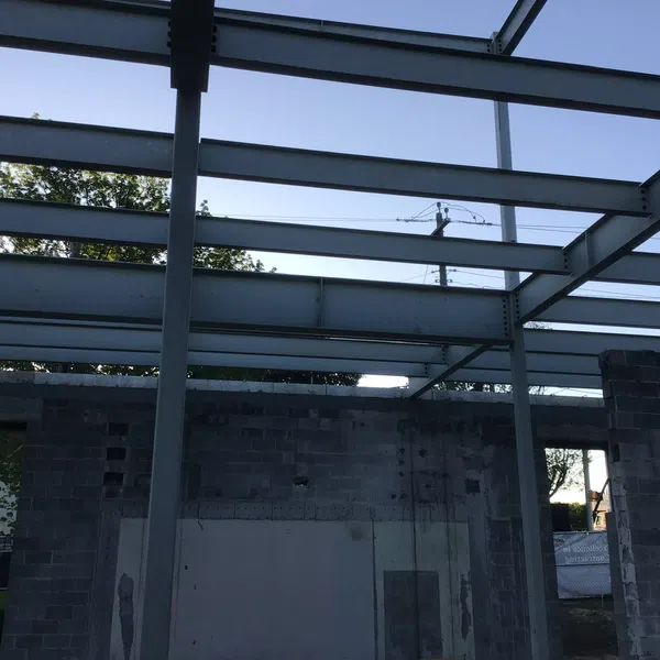 Steel framework and concrete block walls under construction at a building site during daylight.