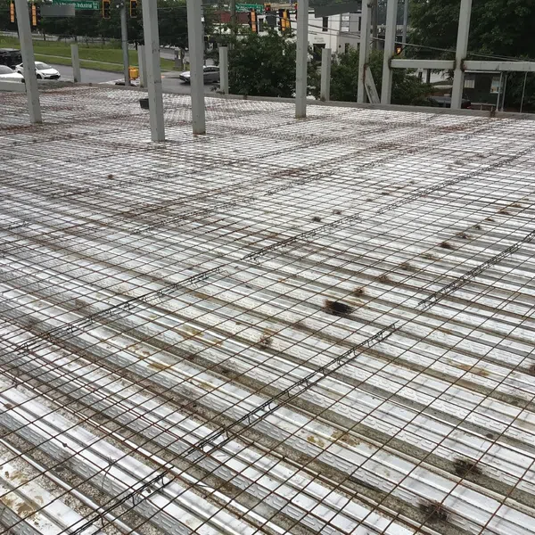 Construction site with steel rebar grid laid over metal decking preparing for concrete pouring.