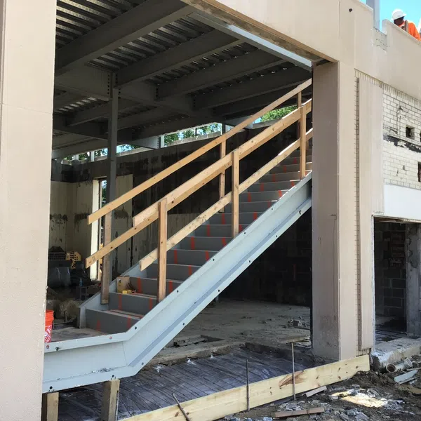 Construction site with steel frame stairs and wooden railings inside unfinished building structure