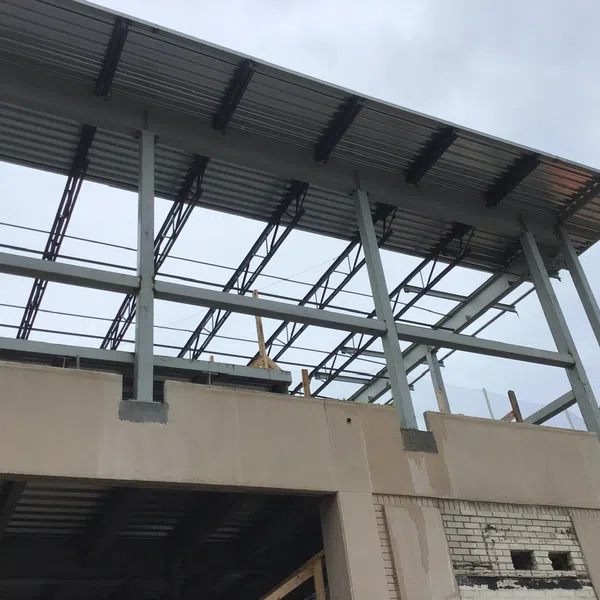 Steel framework and concrete structure of a building under construction on a cloudy day.
