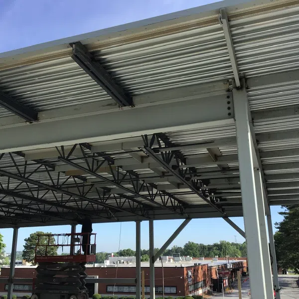Steel framework and roof structure of a commercial building under construction with a lift and workers visible.