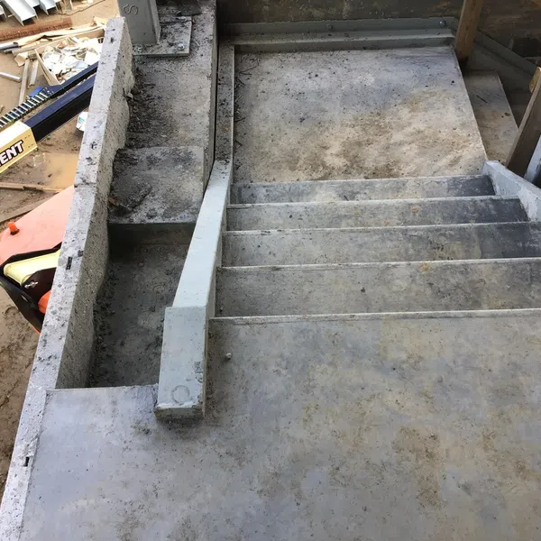Top view of unfinished concrete stairs and surrounding construction area with equipment and dirt.