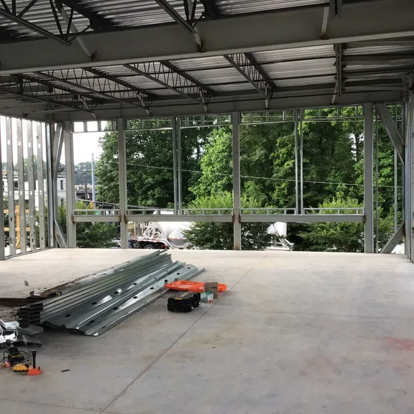 Interior view of a steel-framed building under construction with metal beams and concrete floor.