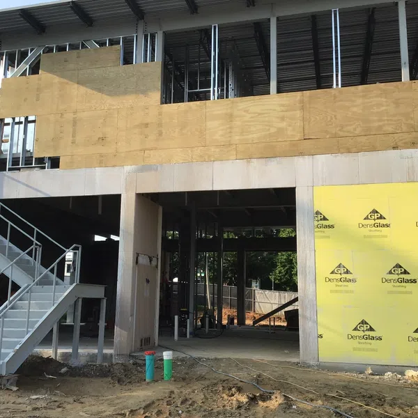 Construction site showing a steel stair structure, plywood walls, and yellow DensGlass sheathing panels.