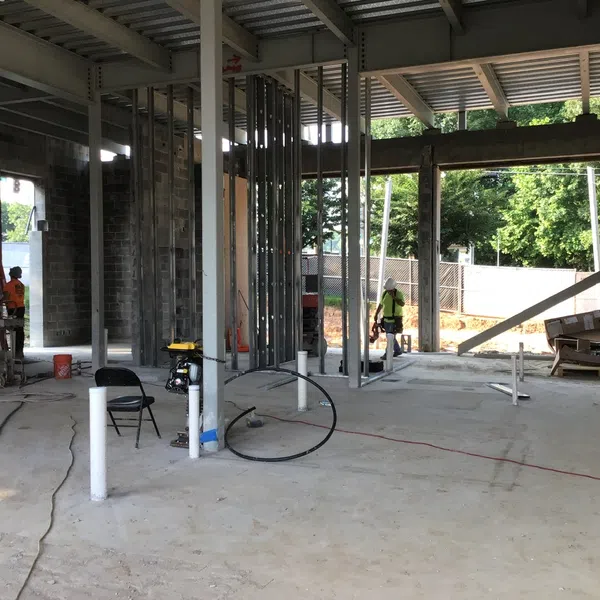 Interior view of an unfinished commercial building under construction with workers and exposed metal framing.
