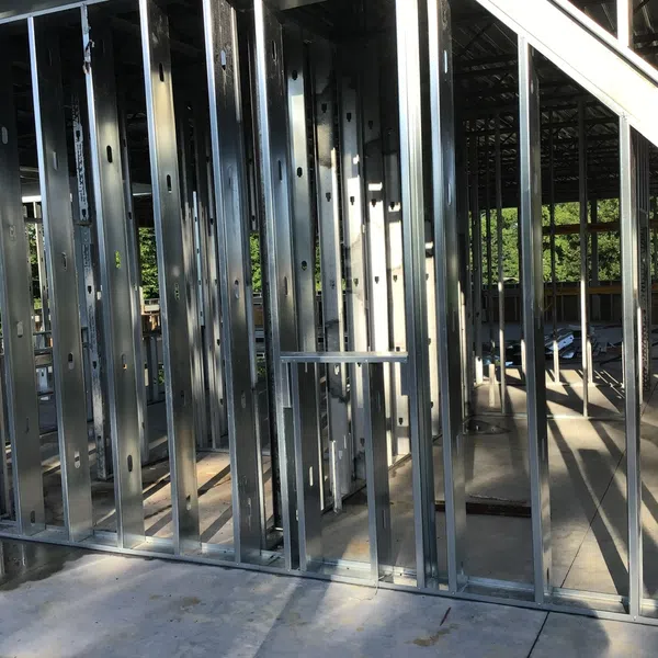 Interior view of a building under construction with exposed metal stud framing and concrete floor in daylight