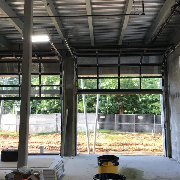 Interior view of a garage under construction with open sectional doors and construction materials scattered inside