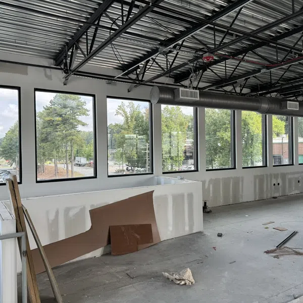 Interior of commercial space under renovation with large windows and exposed ceiling ductwork
