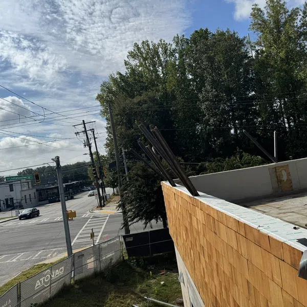 Construction site with wooden wall panels beside a street intersection under a partly cloudy sky