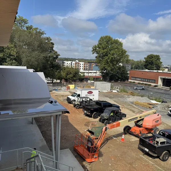 Construction site with trucks, an orange cherry picker, and building materials on a clear day with blue sky.