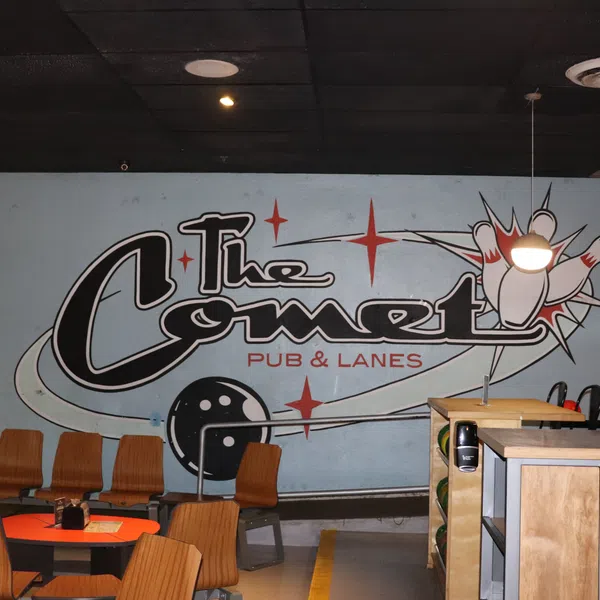 Interior of The Comet Pub & Lanes with bowling decor, wooden chairs, and a mural of pins and a bowling ball.