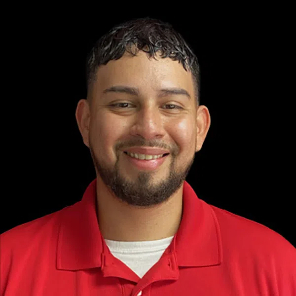 Smiling man with short beard wearing a red collared shirt with a company logo on black background