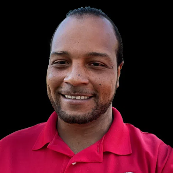 Smiling man wearing a red polo shirt with a construction company logo on a black background