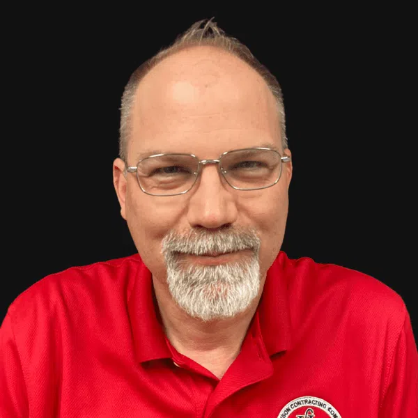 Middle-aged man with glasses and white beard wearing a red polo shirt with Harrison Contracting logo