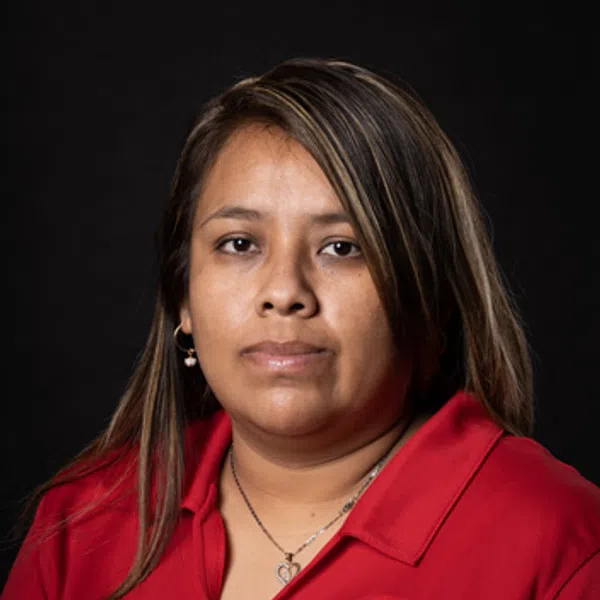 Woman with shoulder-length hair wearing red polo shirt with logo on black background