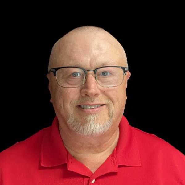 Smiling middle-aged man wearing glasses and a red polo shirt with a construction company logo on black background