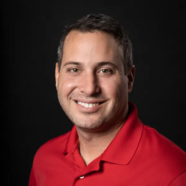 Smiling man in red polo shirt with embroidered logo on black background