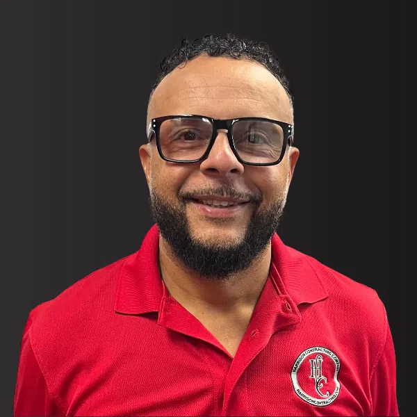 Smiling man with beard and glasses wearing a red polo shirt with Harperson Contracting logo on black background