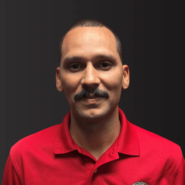 Portrait of a man with a mustache wearing a red polo shirt against a dark background