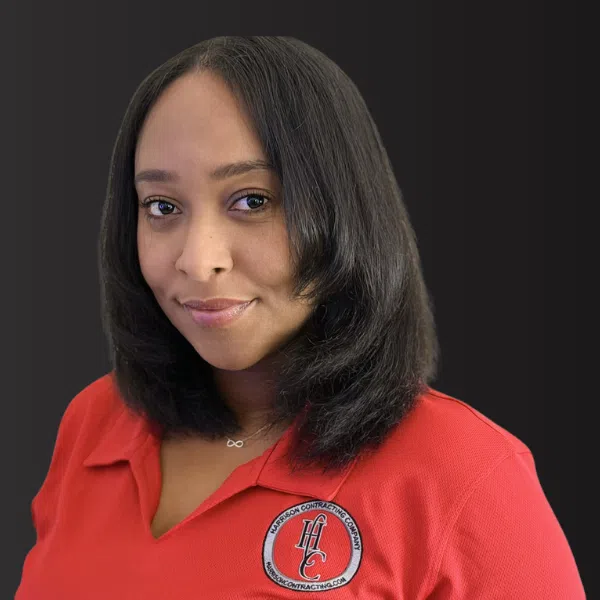 Professional woman with shoulder-length black hair wearing a red shirt with a company logo on a dark background
