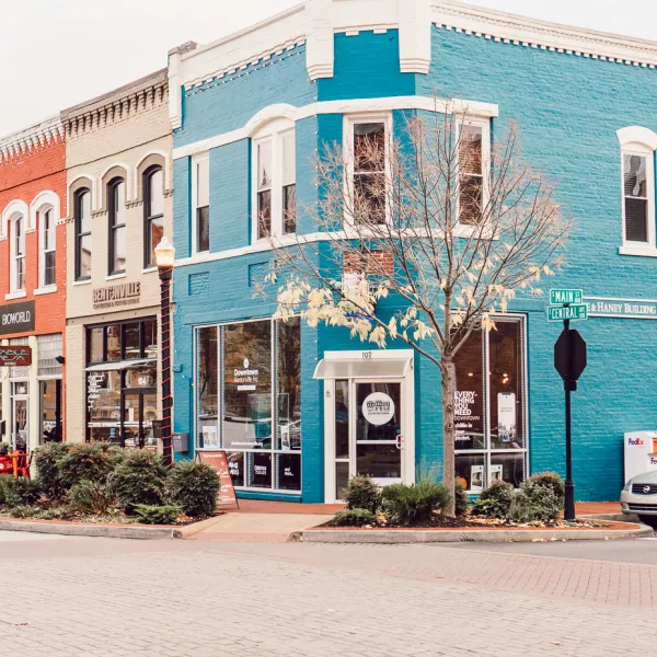 Colorful downtown storefronts with brick and blue buildings, showcasing local shops and street signs.