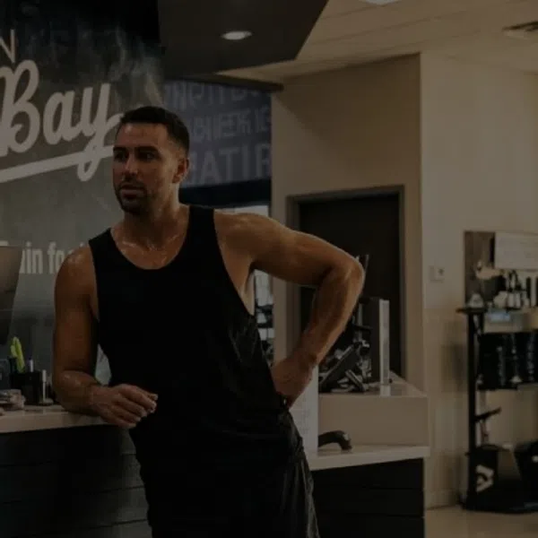 Two men in athletic wear talking at a gym counter with an Afterburn South Bay sign in the background.