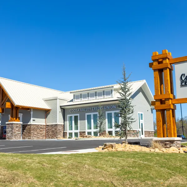 Coosa Valley Credit Union building with stone and wood architectural elements under clear blue sky.