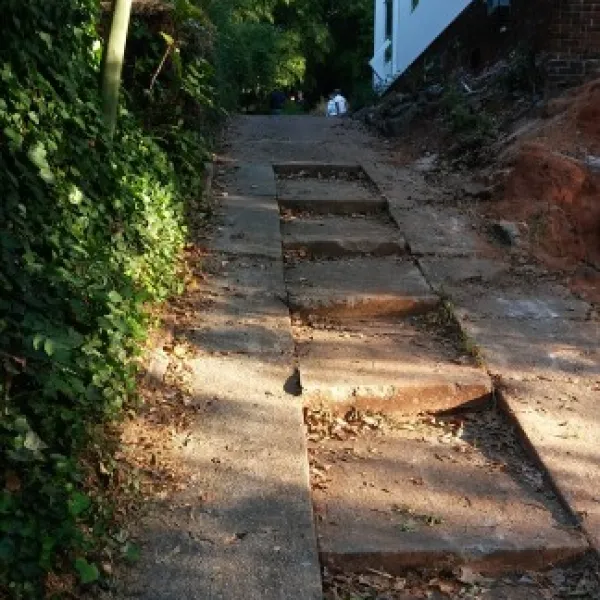 a stone path with a building and trees on the side