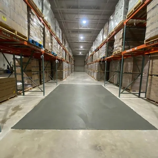 Spacious warehouse aisle lined with shelves of stacked boxes and pallets, well-lit and organized.