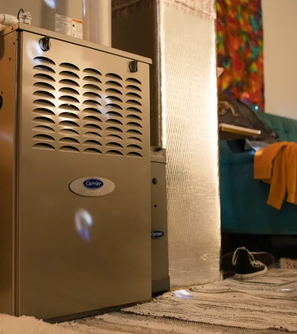 Indoor Carrier brand furnace next to a drum set and cozy living area with teal sofa and colorful wall art.