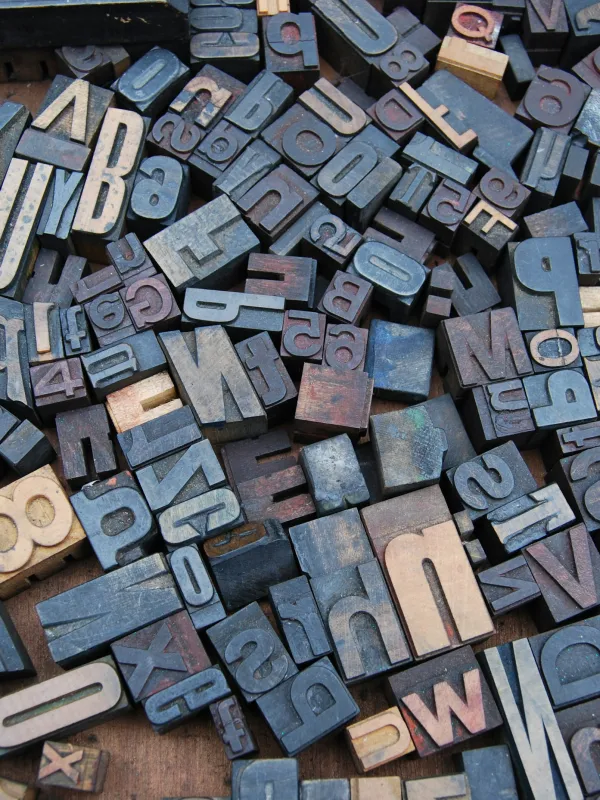 Assorted vintage wooden letterpress blocks scattered on a surface, showcasing various letters and numbers.