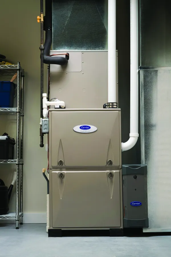 A modern furnace installed in a garage with organized shelves of cleaning supplies and tools.