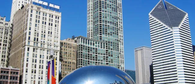 a large reflective sphere in front of a group of tall buildings