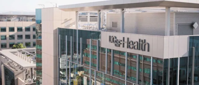 Modern UCSF Health building with glass facade reflecting surrounding urban architecture on a clear day