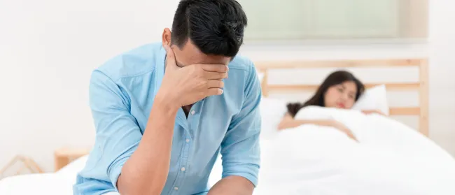 a person sitting on a bed with the hand on the face