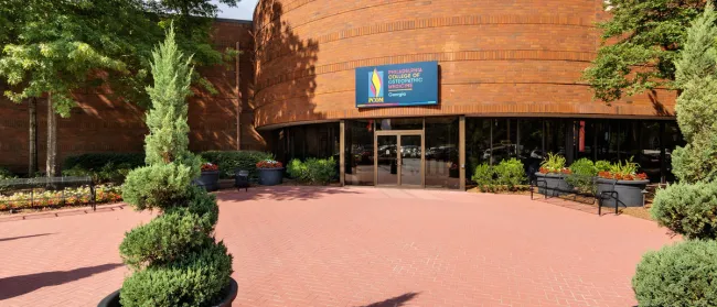South College building with red brick exterior, white columns, dome, and fountains in front under clear blue sky
