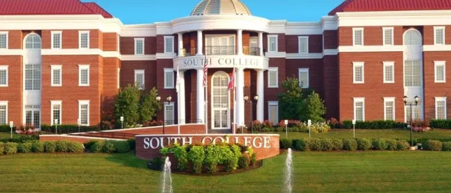 South College building with red brick exterior, white columns, dome, and fountains in front under clear blue sky