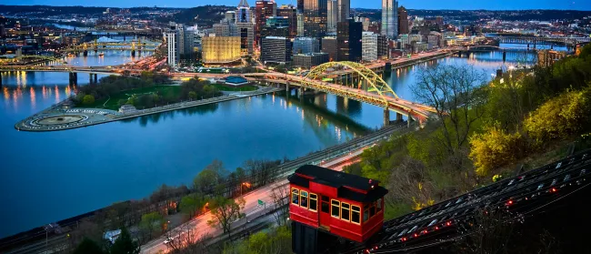 a train on a bridge over a river with a city in the background