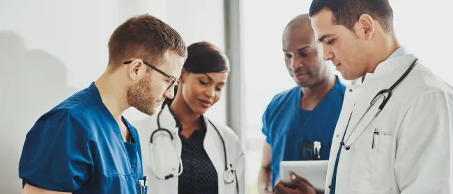 a group of doctors looking at a tablet