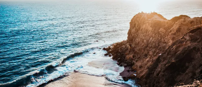 a rocky beach with a body of water in the background