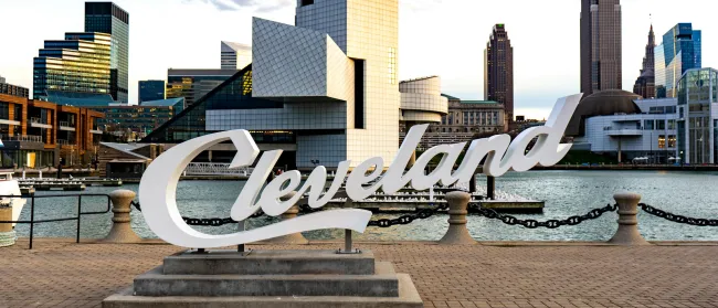 a sign on a brick walkway with a city in the background