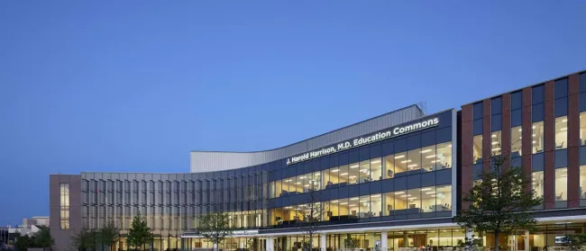 J. Harold Harrison M.D. Education Commons modern building with glass facade and illuminated interior at dusk.