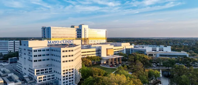 Aerial view of Mayo Clinic hospital complex surrounded by trees under a blue sky at sunset.