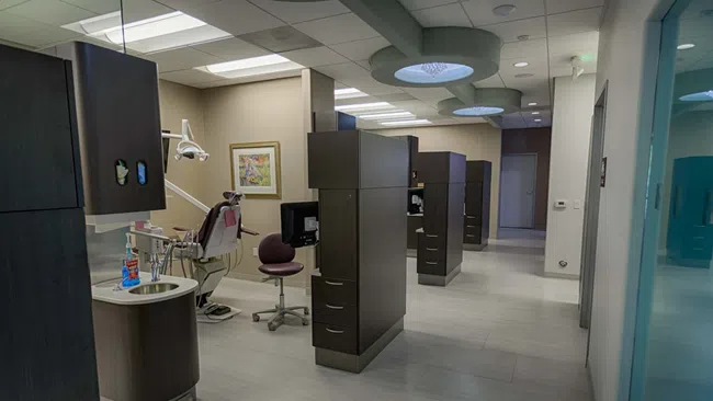 Modern dental clinic interior with dental chair, equipment, and private treatment rooms in neutral tones
